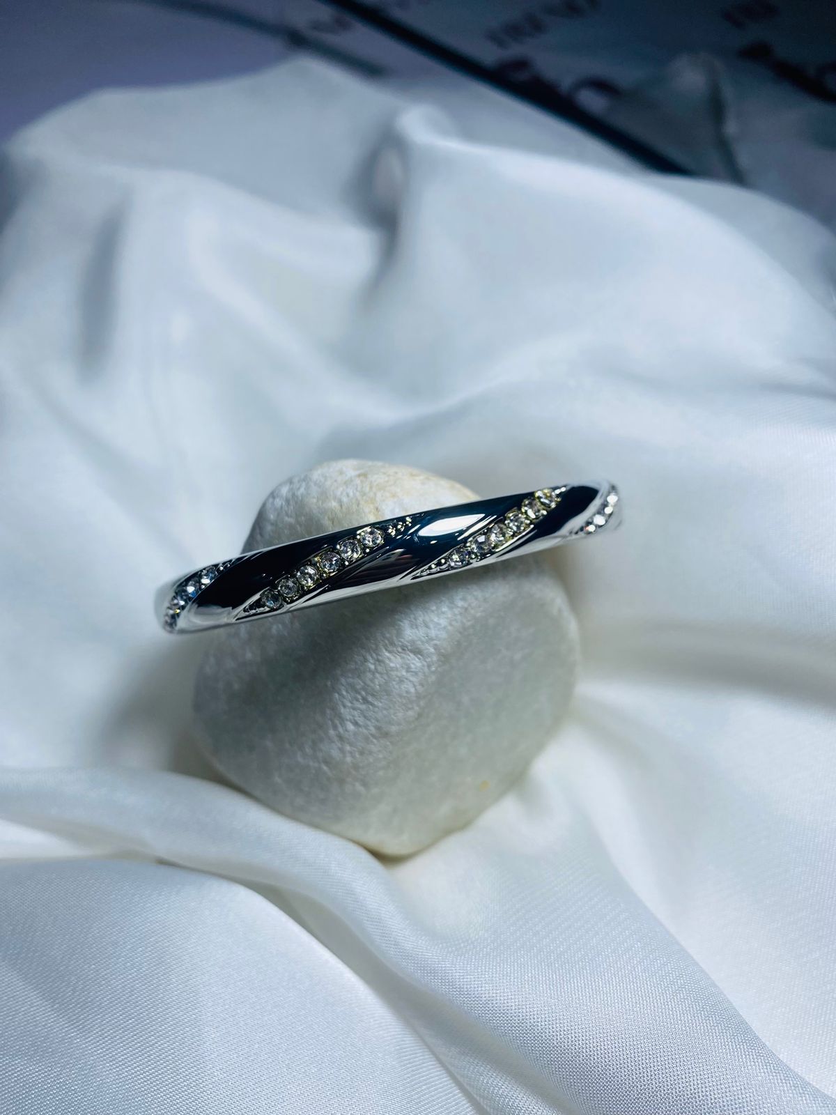 Embellished with small, sparkling cubic zirconia stones along the curves, adding a touch of glamour