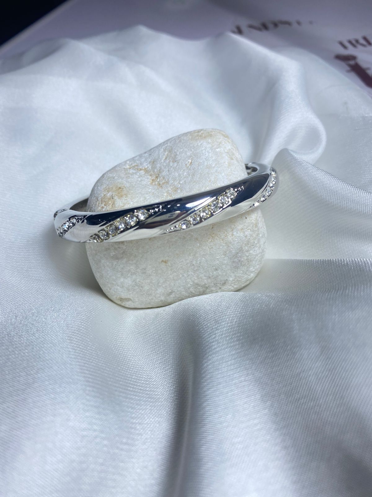 Embellished with small, sparkling cubic zirconia stones along the curves, adding a touch of glamour