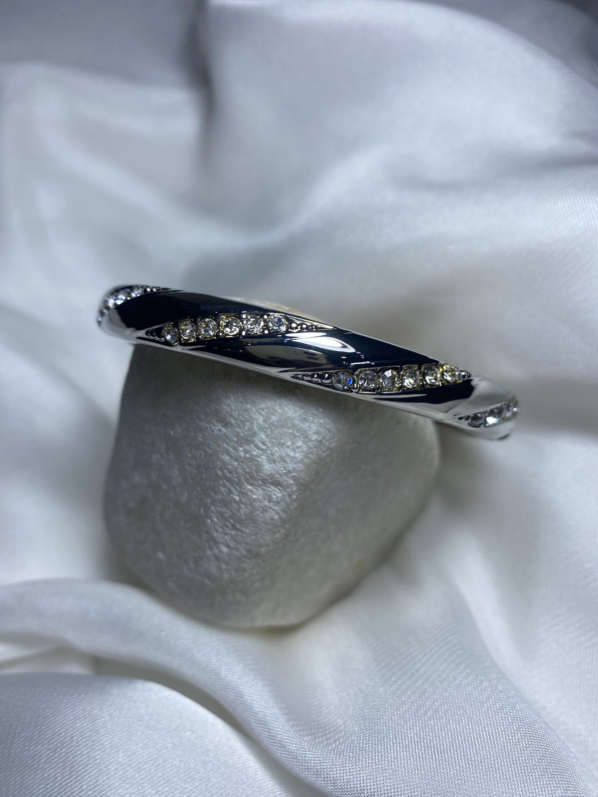 Embellished with small, sparkling cubic zirconia stones along the curves, adding a touch of glamour